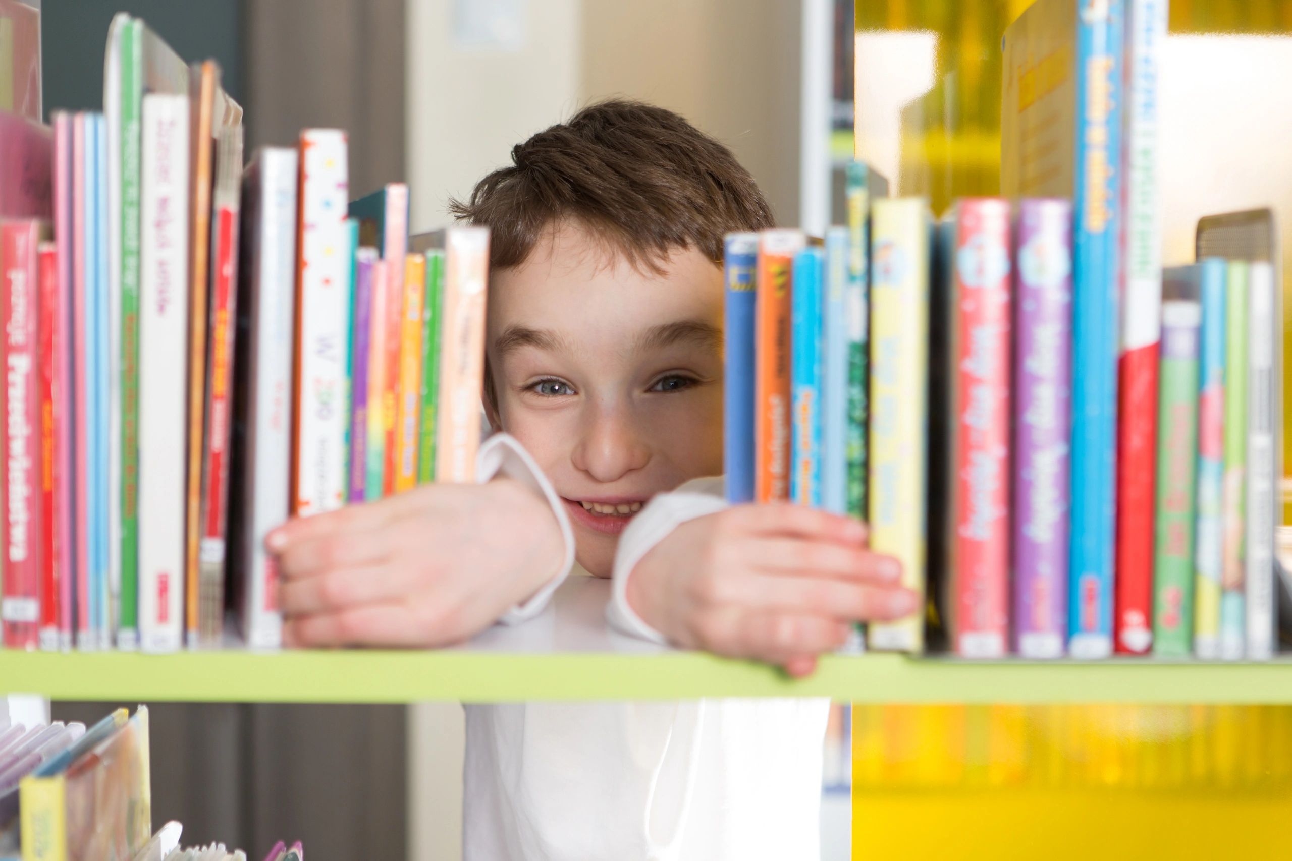 Cute boy reading a book in a library
