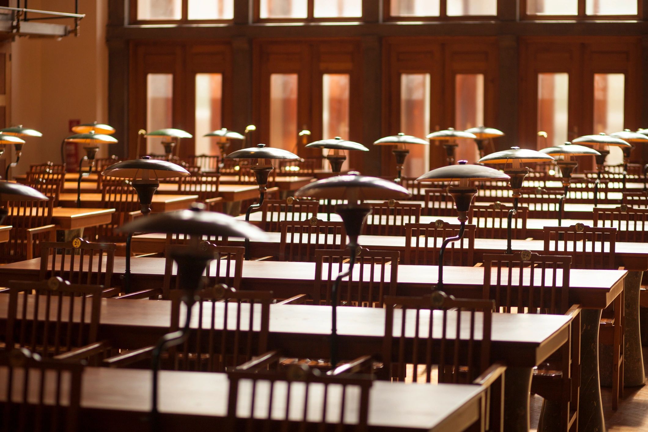 Historic library reading room with long tables and warm natural light