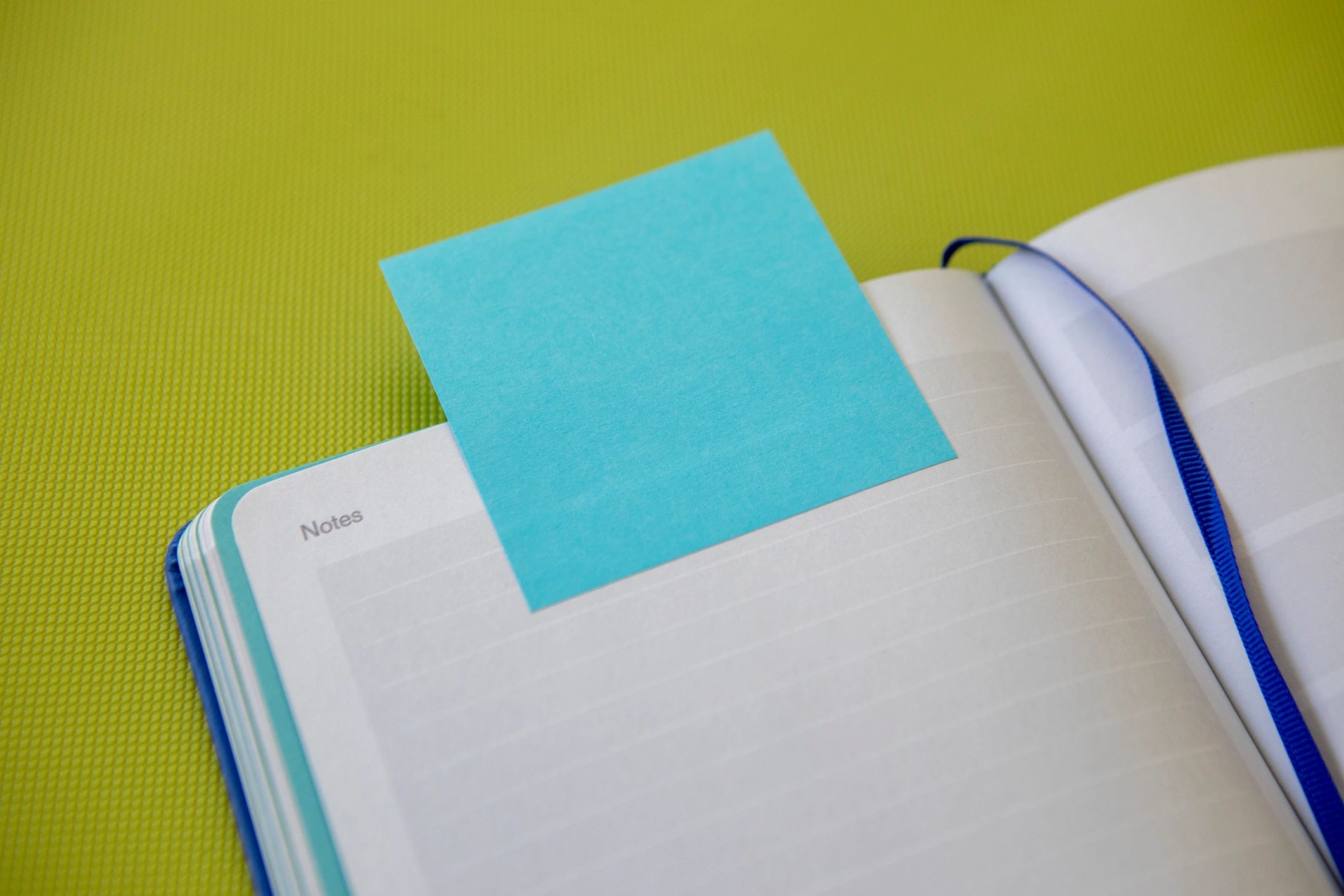 Open notebook with sticky note for weekly writing check-ins