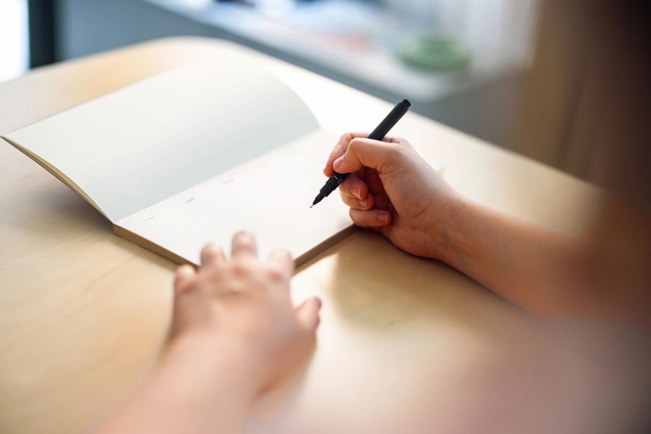 Close-up of writing notes in a notebook on a wooden desk